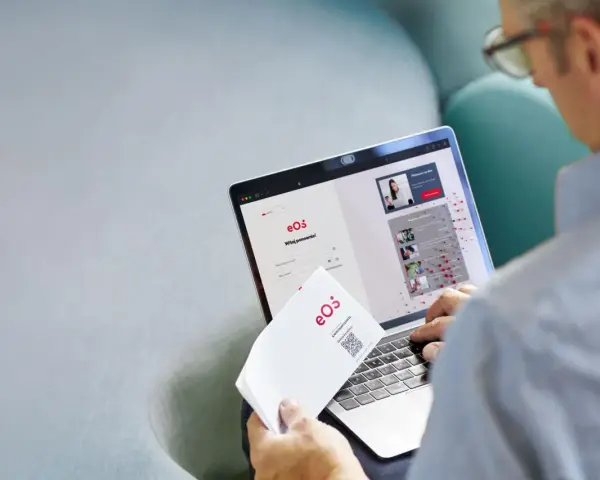 Mężczyzna loguje się do portalu eOS fundusz inwestycyjny. Na ekranie laptopa widnieje formularz logowania i informacje o inwestycjach.