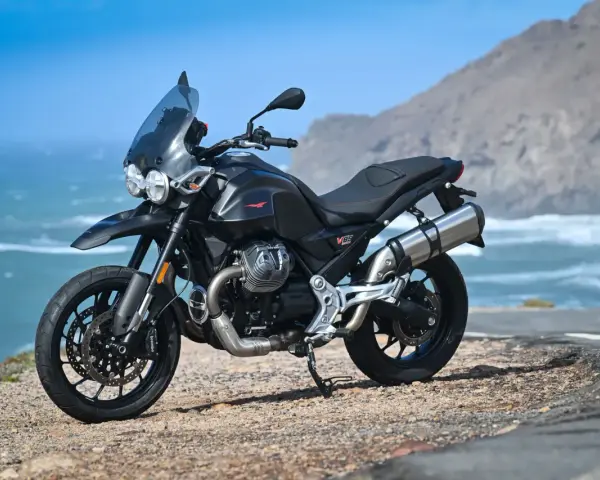 Moto Guzzi V85TT nera, pronta per esplorare, con la sua velocità massima che promette avventure sul mare.