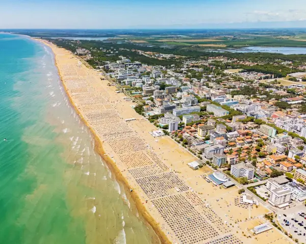 Słoneczna bibione plaża tętni życiem. Tysiące leżaków i parasoli tworzą barwny dywan na piasku, a turkusowe morze zaprasza do kąpieli.