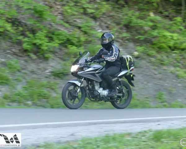 Motocyklista pokonuje zakręt na przełęczy Przysłup, otoczony zielenią górskich zboczy.