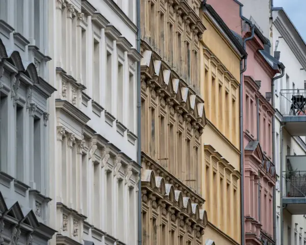Reihenhausfassaden in verschiedenen Farben, von Grau über Beige bis Rosa. Ein Blick auf den m2 preis wohnung in dieser Gegend.