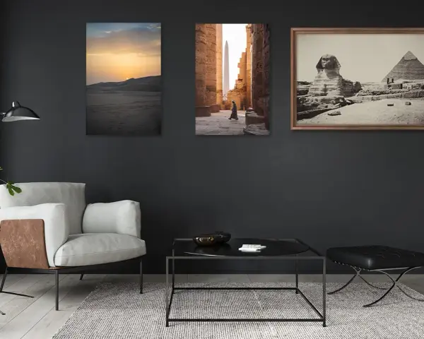 Trois tableaux sur un mur sombre : un coucher de soleil sur les dunes, une personne marchant dans un temple égyptien, et le Sphinx et les pyramides. La **couleur référence** de la pièce est le gris anthracite.