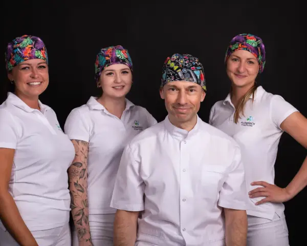 Cztery osoby w białych uniformach i kolorowych czepkach na czarnym tle.