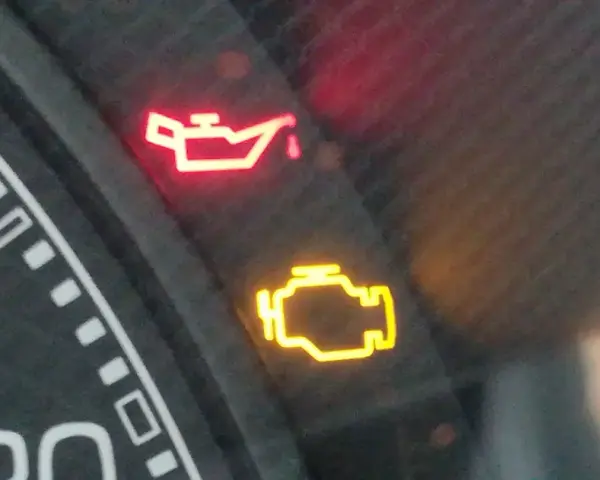 Cruscotto auto con spia dell'olio accesa in rosso e spia motore gialla. Urgente controllo.