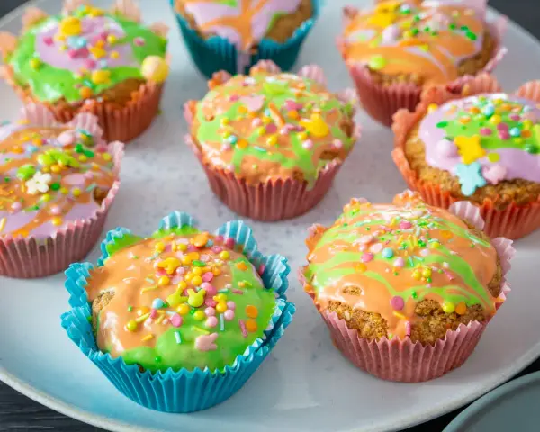 Bunte Karottenmuffins mit Zuckerguss und Streuseln, perfekt für ein Frühlingsfest. Dieses Karottenmuffins Rezept ist ein Hit!