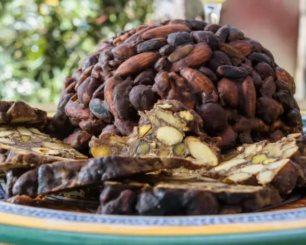Un pan pepato a forma di cupola, ricoperto di mandorle e cacao, con fette tagliate che rivelano frutta secca e spezie.