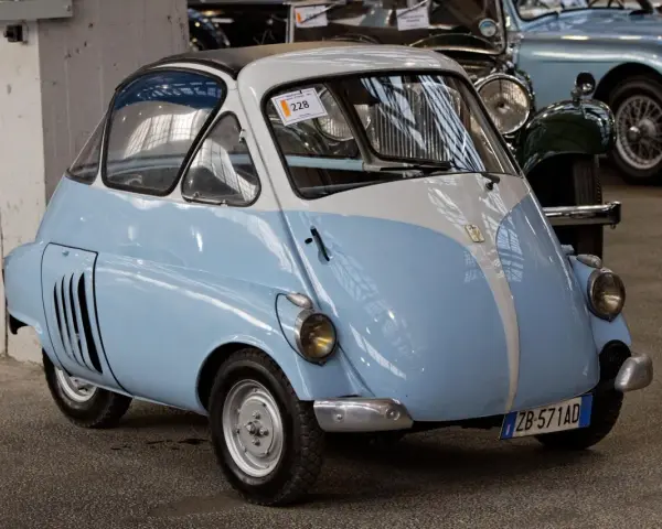 Urocze, błękitno-białe BMW Isetta z lat 50. z charakterystycznymi drzwiami z przodu, gotowe na przejażdżkę po mieście.