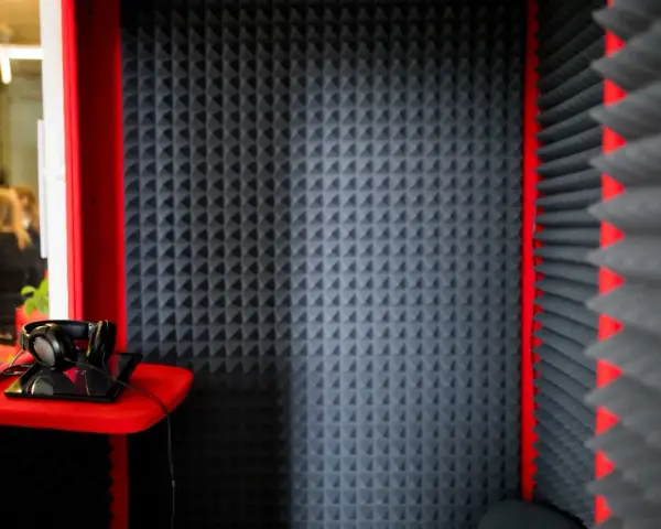 Cabina insonorizzata con pannelli fonoassorbenti, cuffie e tablet. Ideale per registrazioni audio.