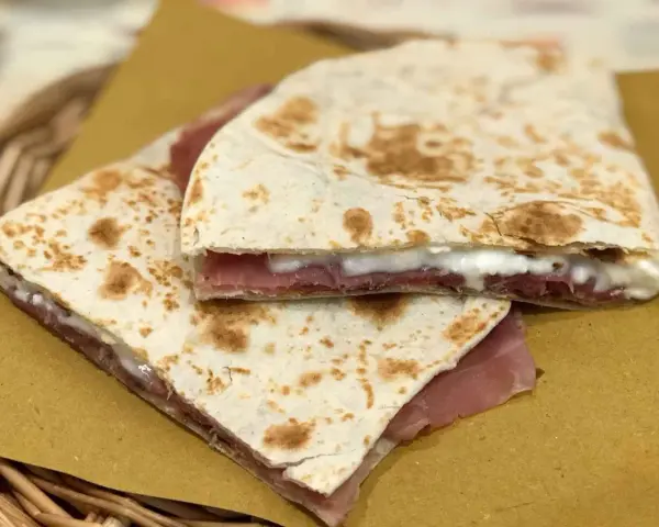 Piadine ripiegate con prosciutto e formaggio cremoso, semplici ingredienti piadina che creano un sapore delizioso.