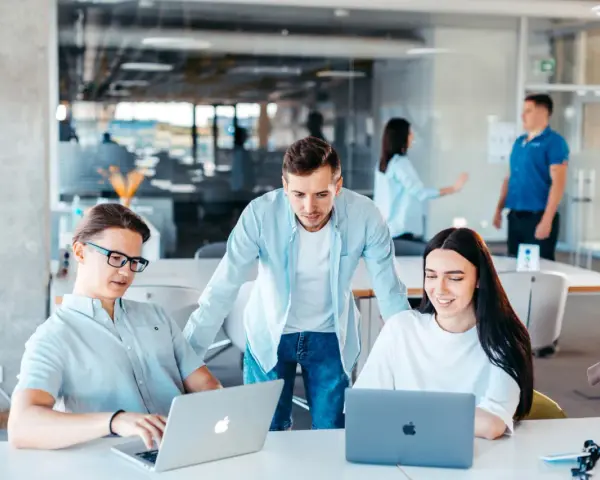 Equipo colabora en un proyecto, usando laptops y aplicaciones informáticas para gestionar la cuenta contable.