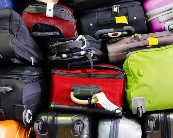 A large pile of various suitcases and bags in different colors, stacked high.