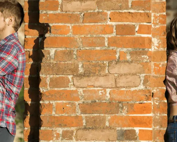 Un homme et une femme se tournent le dos, appuyés contre un mur de briques. Peut-on fixer quelque chose sur un mur mitoyen ?