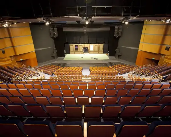 Pusta widownia Teatru Muzycznego im. Danuty Baduszkowej. Pomarańczowe fotele czekają na widzów, scena gotowa na spektakl.