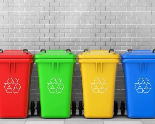 Czerwony, zielony, żółty i niebieski pojemnik na śmieci z symbolem recyklingu. Różne kolory pojemników na śmieci ułatwiają segregację.