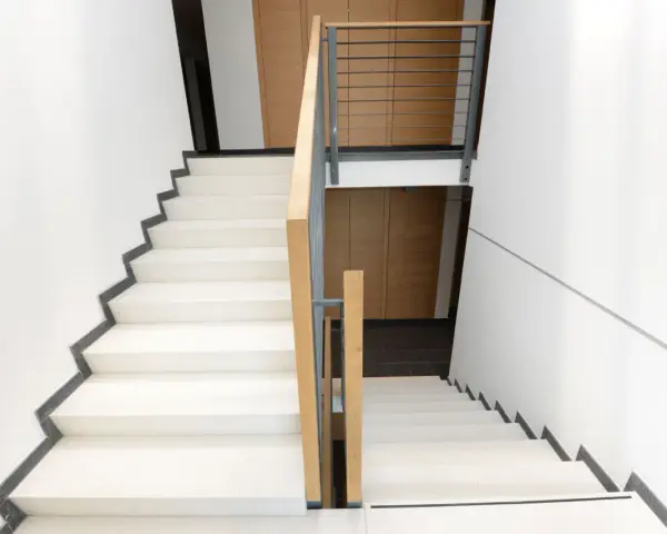 Nowoczesne schody z jasnymi stopniami i drewnianą balustradą. Każdy podstopnica jest wyraźnie zaznaczona.