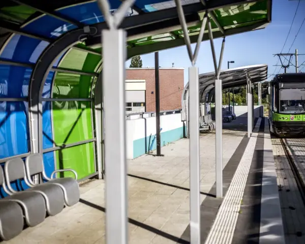 Nowoczesny przystanek tramwajowy w Szczecinie. Zielony tramwaj czeka na pasażerów. Jak dojechać do centrum?