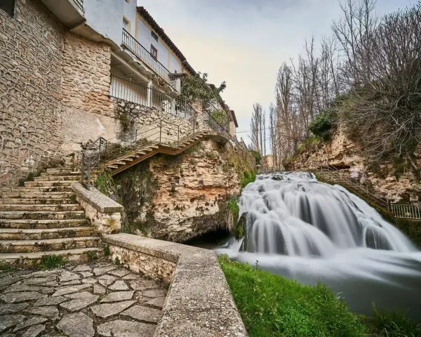 Escaleras de piedra y un caserío se funden con la cascada en la Alcarria Alta.
