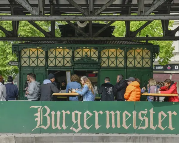 Menschen sitzen an Tischen vor dem Burgermeister in Berlin.