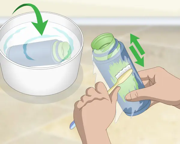 Brosse pour nettoyer peinture acrylique sèche sur une bouteille. Une autre bouteille trempe dans un bol d'eau.