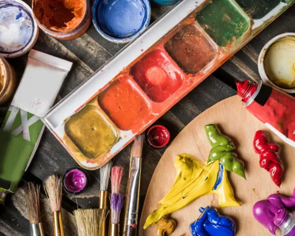 Palette de couleurs vives pour une peinture à l'acrylique. Tubes de peinture, pinceaux et pots de couleurs sont prêts pour la création artistique.