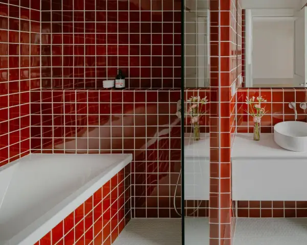 Salle de bain aux carreaux rouges vifs. La question "faut il carreler toute la salle de bain" se pose face à cette audace. Baignoire, lavabo et douche sont intégrés.