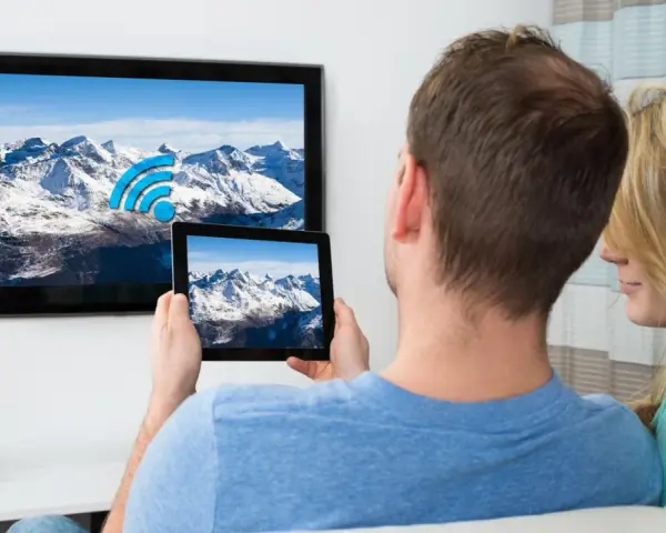 Ein Paar verbindet sein iPad mit dem Fernseher, um die Berglandschaft auf dem großen Bildschirm zu genießen.