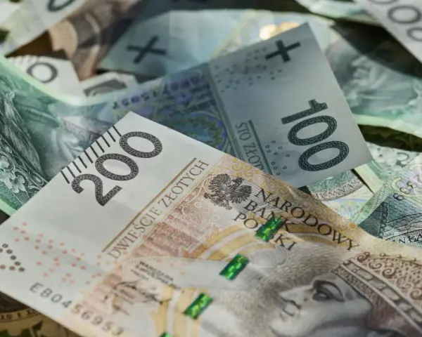 Złotówki, w tym banknot 200 zł, tworzą stos. Marzenia o wakacjach w 2026 roku? Trzynastka pomoże!