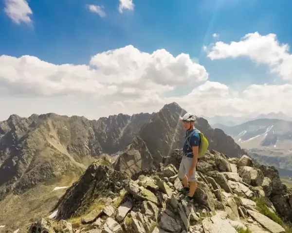 Turysta na skalistym szczycie, wskazujący drogę na Orlej Perci. W tle majestatyczne Tatry.