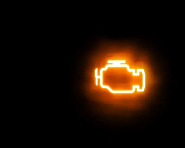 Icona luminosa arancione di un motore su sfondo nero. La spia MIL accesa indica un problema.