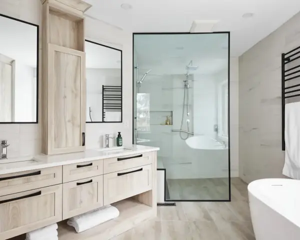 Salle de bain moderne avec double vasque en bois clair, douche vitrée et baignoire îlot. Un design épuré pour une ambiance zen.