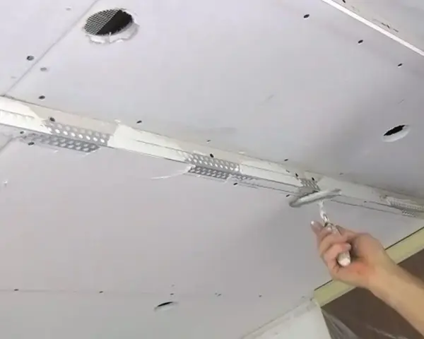 Hand spachtelt Rigipsdecke, um eine glatte Oberfläche für den Innenausbau zu schaffen.