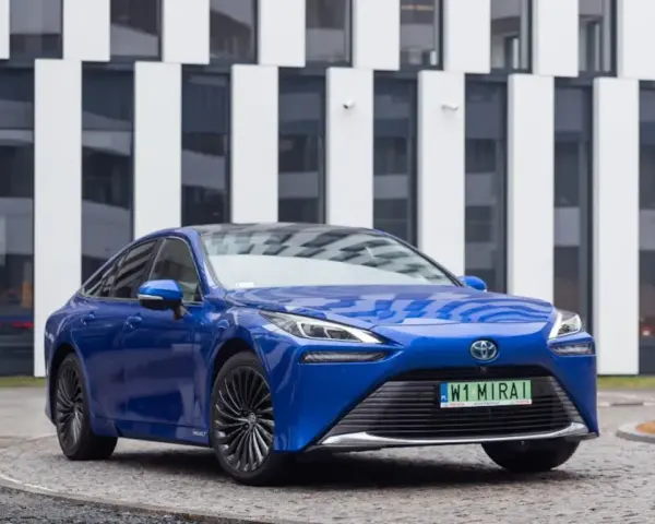 Niebieski samochód Toyota Mirai na tle nowoczesnego budynku.
