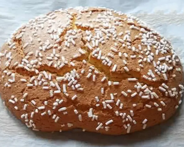 Ciambella romagnola artusi, soffice e dorata, cosparsa di zuccherini bianchi. Un dolce che sa di casa e tradizione.