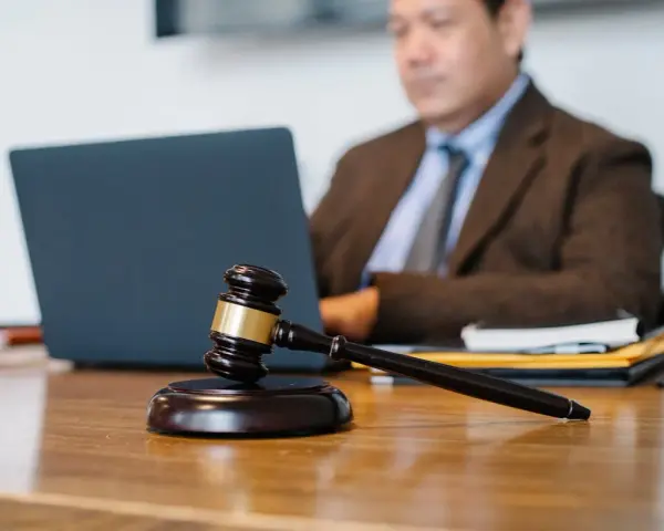 Sądowy młotek na biurku, prawnik pracuje przy laptopie. Dyskrecja w ujawnieniu informacji o zadłużeniu osobom trzecim.