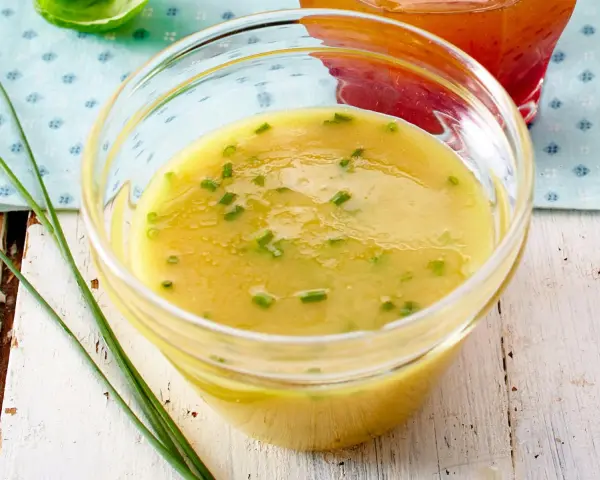 Ein Glas mit cremigem honig senf dressing, garniert mit Schnittlauch. Perfekt für einen frischen Salat.