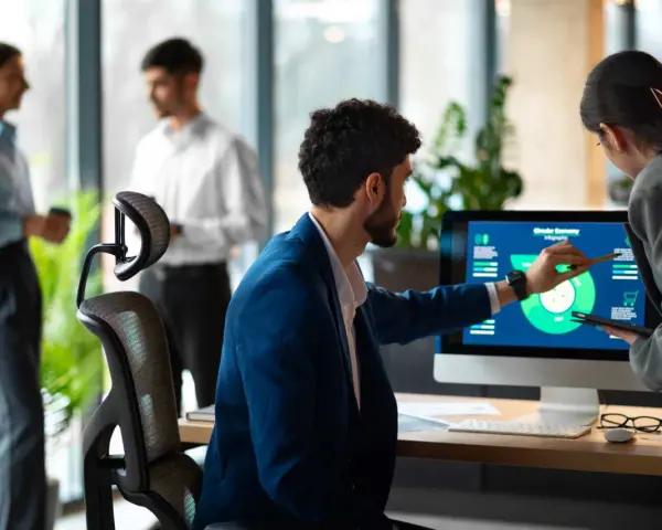 Uomini e donne discutono di grafici su un monitor, esplorando nuove opportunità di lavori del futuro senza laurea.