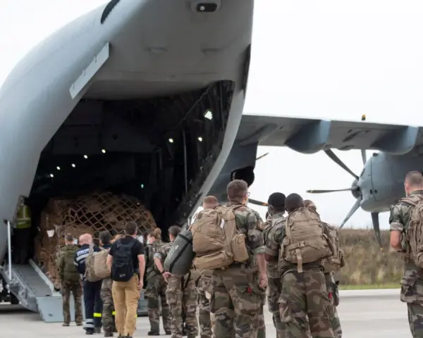 Soldaten mit Rucksäcken stehen vor einem Frachtflugzeug, bereit für ihren Einsatz im Afghanistan-Krieg.