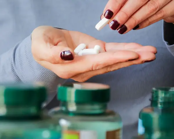 Frau nimmt Pillen, darunter 5-HTP, aus ihrer Hand.