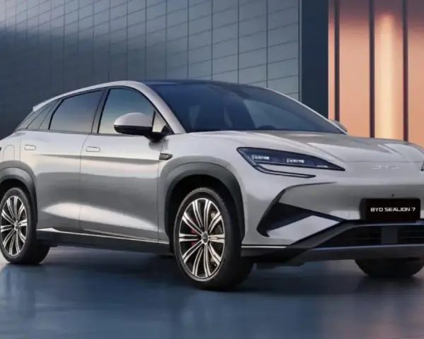Srebrny SUV BYD Sealion 7 z nowoczesnym designem, zaparkowany przed budynkiem.