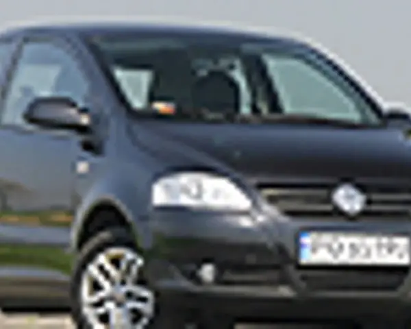 Czarny VW Fox z polskimi tablicami rejestracyjnymi stoi na tle zieleni.