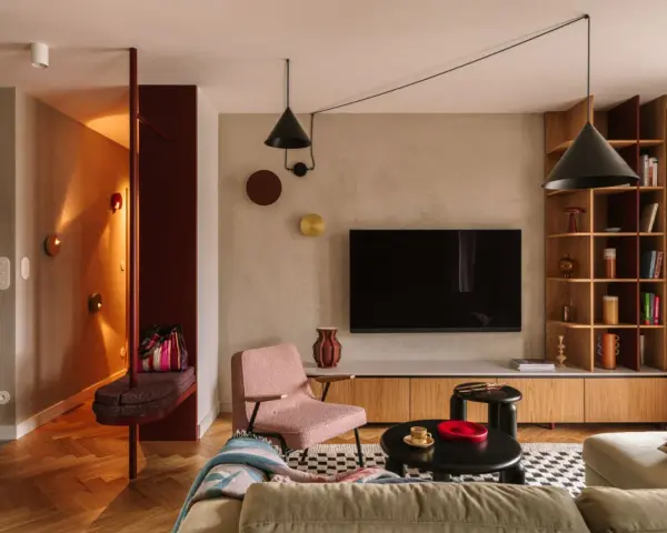 Nowoczesny salon z elementami boho. Wygodna kanapa, różowy fotel, czarne stoliki i regał. W przedpokoju ławka i lustro. Idealne miejsce na relaks po całym dniu. Ten **kosztorys remontu** był wart każdej złotówki.