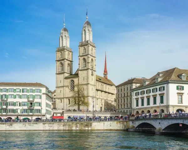 Zurych co warto zobaczyć: imponująca katedra Grossmünster z dwiema wieżami, rzeka Limmat i most.