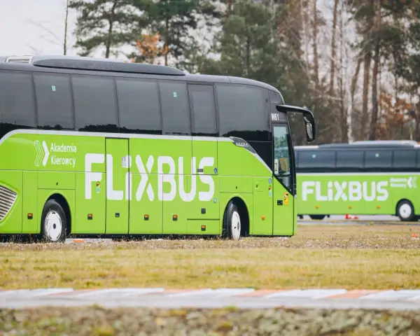 Zielony autobus Flixbus z napisem "Akademia Kierowcy" stoi na trawie. Czyżby kolejne flixbus opóźnienia?