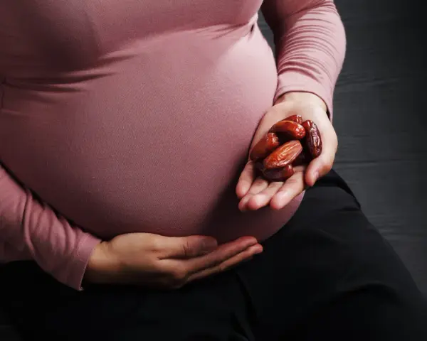 Kobieta w ciąży trzyma w dłoni garść daktyli. To naturalny sposób na wsparcie organizmu w tym wyjątkowym czasie.