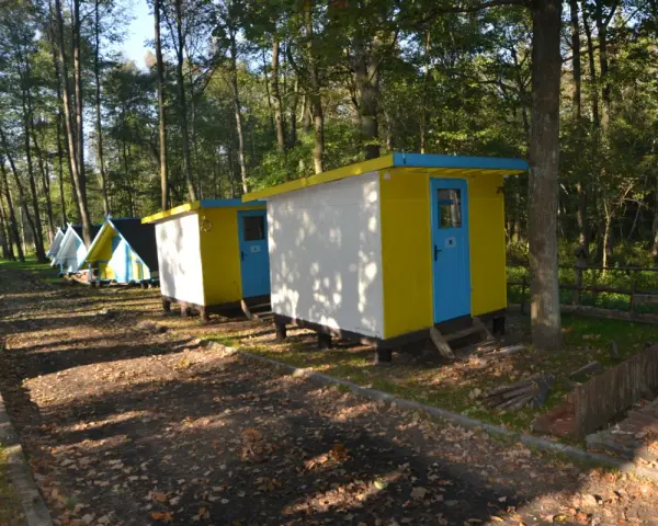 Kolorowe domki kempingowe w lesie, jak małe perły Krutyni, czekają na gości.