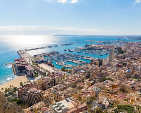 Widok na port jachtowy i plażę w słoneczny dzień. Tak właśnie wygląda Alicante, gdzie jest to piękne miasto.