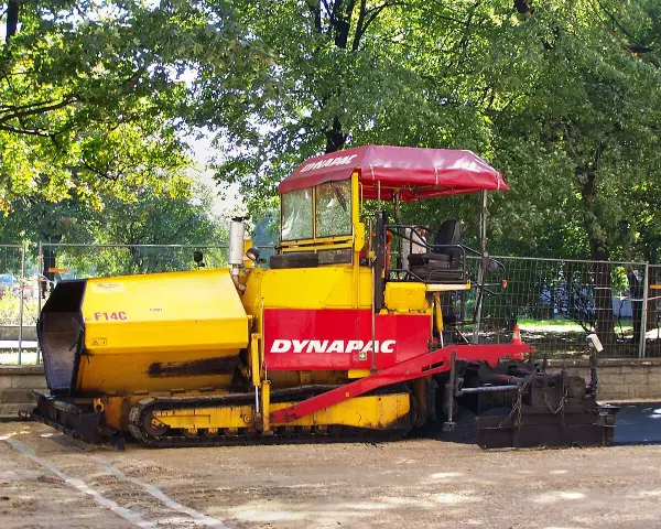 Żółto-czerwony rozściełacz do kruszywa Dynapac F14C na placu budowy.