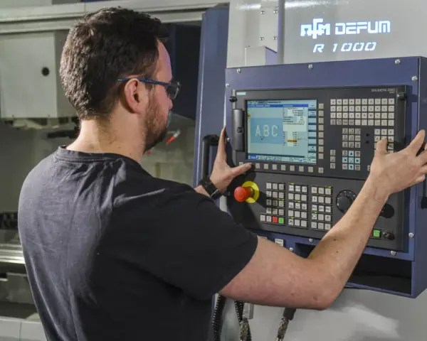 Operator CNC przy panelu sterowania. Dobra praca to wysokie operator cnc zarobki.