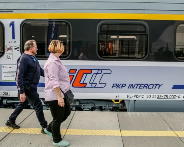 Para podróżuje obok pociągu PKP Intercity, który może zabrać ich z Rzeszowa do Krakowa.
