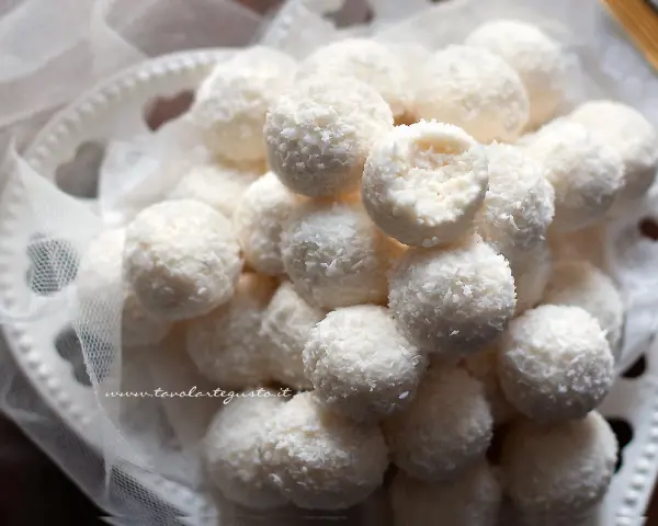Dolci palline di cocco, morbide e profumate, adagiate su un piatto decorato con un velo di tulle.